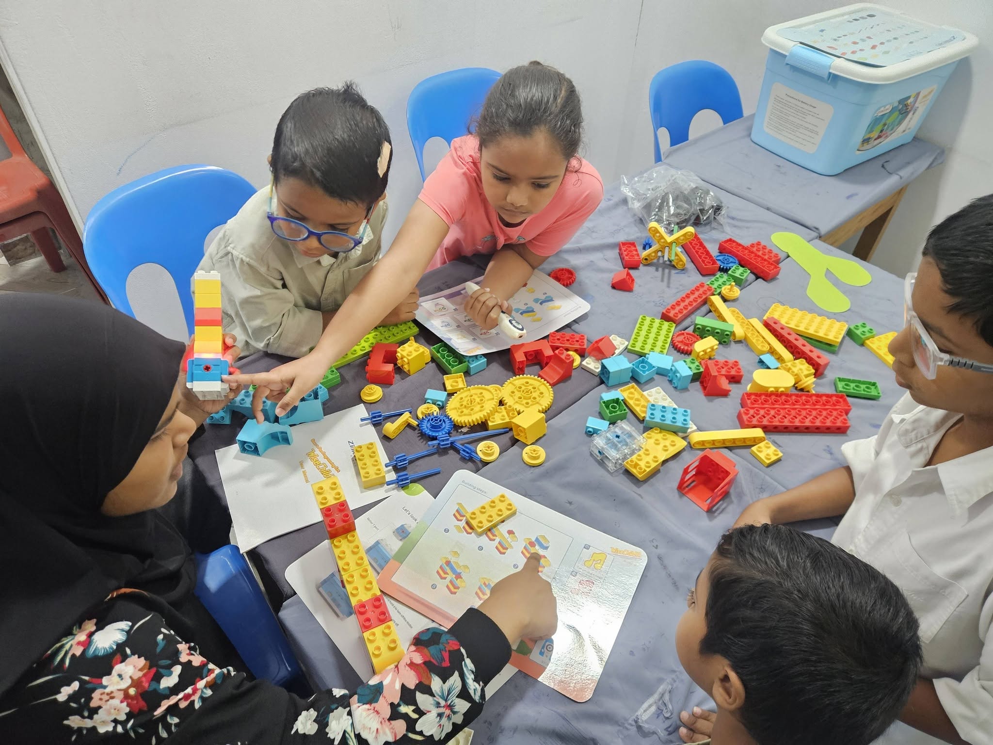 Children building with colorful robotics blocks in a STEM class